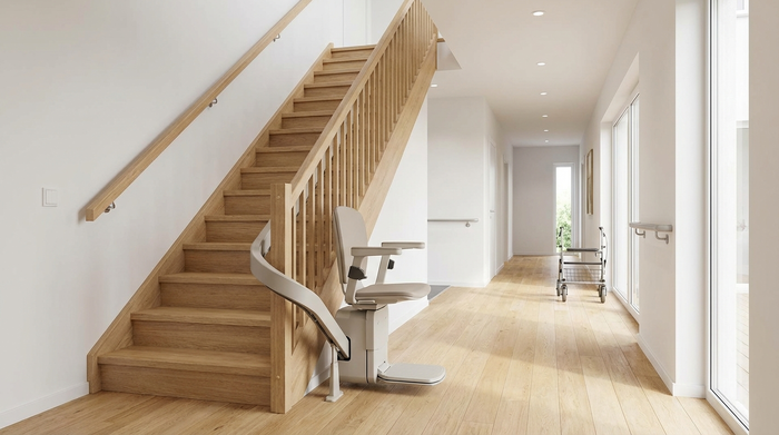Ein moderner, unauffälliger Treppenlift ist an einer hellen Holztreppe in einem gepflegten, barrierefreien Flur installiert. Die Umgebung ist aufgeräumt, hell beleuchtet und strahlt ein sicheres Wohnumfeld aus. Fotorealistische Darstellung ohne Text.