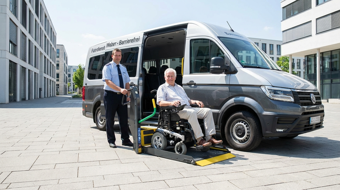 Ein professioneller Fahrer bedient die hydraulische Hebebühne eines modernen Kleinbusses. Ein älterer Herr sitzt entspannt und sicher in einem Rollstuhl auf der Rampe. Sonniges Wetter, klare und sichere Umgebung.