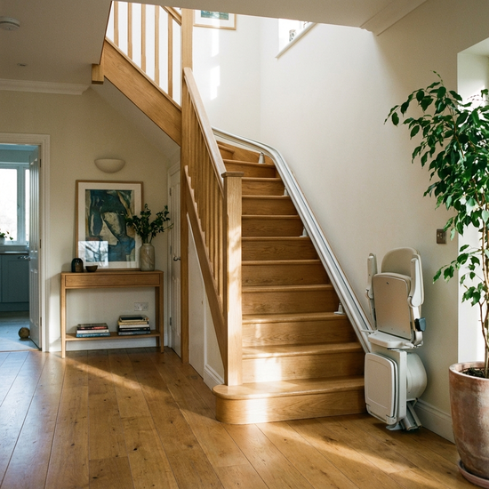 Ein eleganter, unauffälliger Treppenlift ist an einer Holztreppe in einem gepflegten Einfamilienhaus installiert.