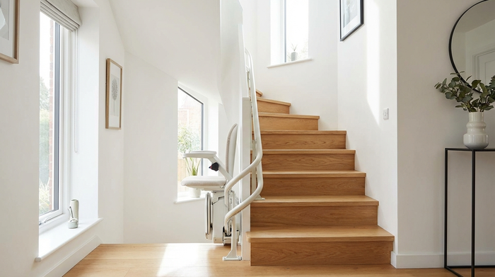 Ein moderner, unauffälliger Treppenlift in einem gepflegten, hellen Treppenhaus eines Einfamilienhauses. Hochwertige Holzstufen, weiße Wände, sicheres und barrierefreies Wohnen.