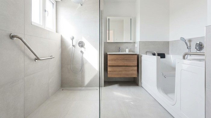 Ein modernes, helles und barrierefreies Badezimmer mit einer großzügigen, bodengleichen Dusche und einem eleganten Haltegriff an der Wand. Alles ist sauber, sicher und stilvoll eingerichtet.
