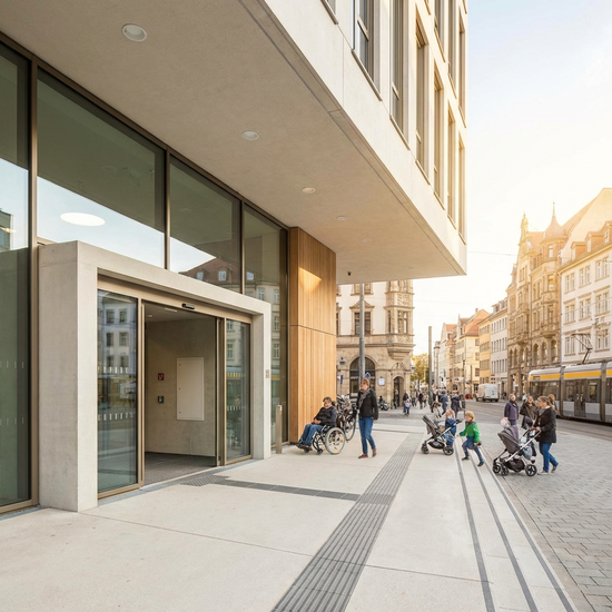 Ein modernes, barrierefreies Gebäudeportal in einer deutschen Stadt an einem sonnigen Tag, saubere Architektur, einladender Eingangsbereich ohne lesbare Schilder.