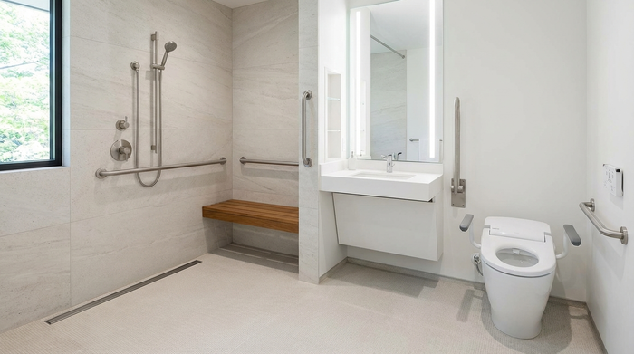 Ein modernes, helles und komplett barrierefreies Badezimmer mit einer bodengleichen Dusche, eleganten Haltegriffen an den Wänden und einem rutschfesten Boden. Die Einrichtung ist stilvoll, makellos sauber und maximal sicher gestaltet.