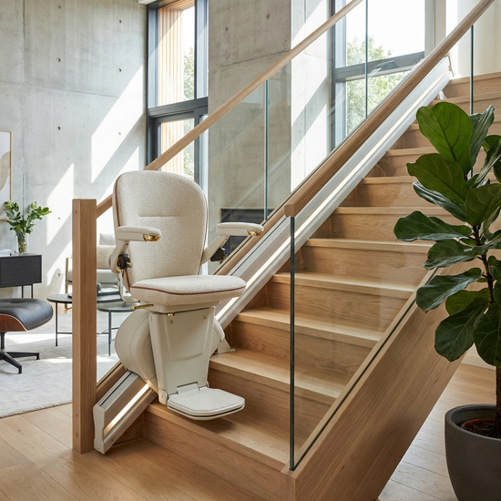 Ein eleganter, gepolsterter Treppenlift an einer hellen Holztreppe in einem gepflegten, modernen Einfamilienhaus.