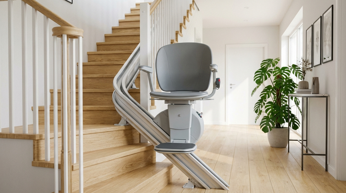 Ein moderner Treppenlift ist an einer hellen Holztreppe in einem gepflegten Einfamilienhaus installiert. Im Hintergrund sieht man einen sauberen Flur mit einer großen, grünen Zimmerpflanze. Fotorealistisch, ordentliches Umfeld.