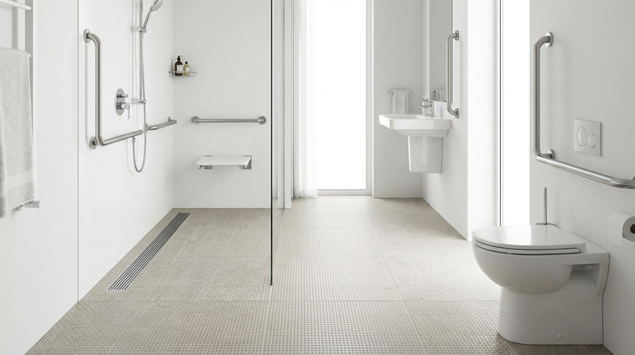 Ein helles, barrierefreies und modernes Badezimmer mit einer großzügigen, ebenerdigen Dusche, rutschfesten Fliesen und sicheren Haltegriffen an den weißen Wänden.