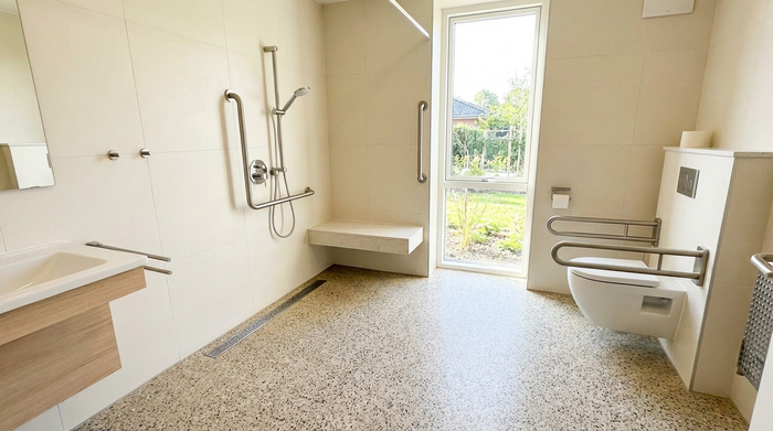 Ein modernes, barrierefreies Badezimmer mit einer bodengleichen Dusche, eleganten Haltegriffen und einem rutschfesten Boden. Helle Fliesen und viel Tageslicht sorgen für eine angenehme Atmosphäre. Realistisch und ohne Text.