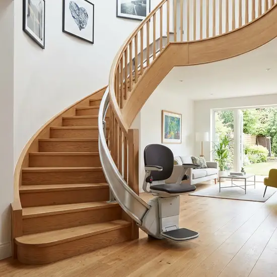 Ein eleganter, moderner Treppenlift, der an einer geschwungenen Holztreppe in einem gepflegten Einfamilienhaus installiert ist.