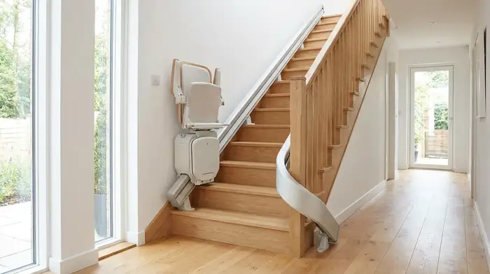Ein eleganter, moderner Treppenlift ist an einer hellen Holztreppe in einem gepflegten Einfamilienhaus installiert. Das Design ist unauffällig und fügt sich harmonisch in den Flur ein.
