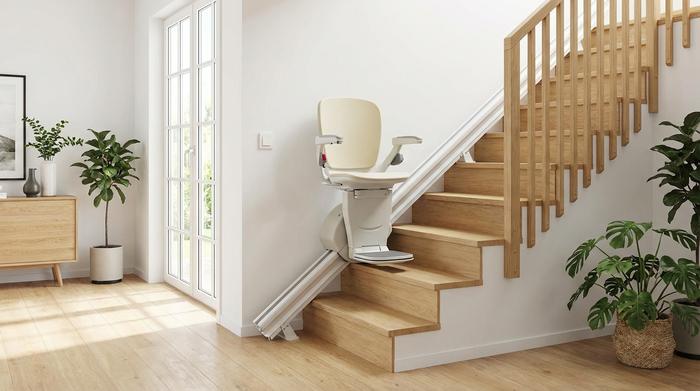 Ein moderner, sauberer Treppenlift an einer hellen Holztreppe in einem gepflegten Einfamilienhaus. Die Schienen verlaufen ordentlich an der weißen Wand.
