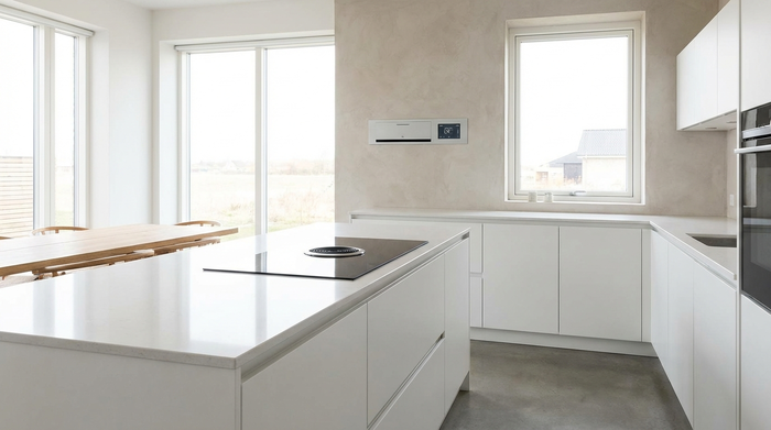 Eine aufgeräumte, moderne Küche mit hellen Arbeitsplatten. Ein moderner Elektroherd mit einer unauffälligen Sensor-Einheit an der Wand darüber. Keine gefährlichen Gegenstände oder Kabel auf den Arbeitsflächen. Helles Tageslicht fällt durch das Fenster. Realistisch und ordentlich.