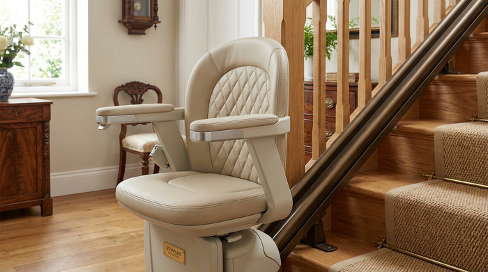 Ein detaillierter Blick auf einen hochwertigen Treppenlift-Sitz aus hellem Leder, der an einer geraden Schiene auf einer Holztreppe montiert ist. Fokus auf die saubere Verarbeitung und das elegante Design im Innenbereich.