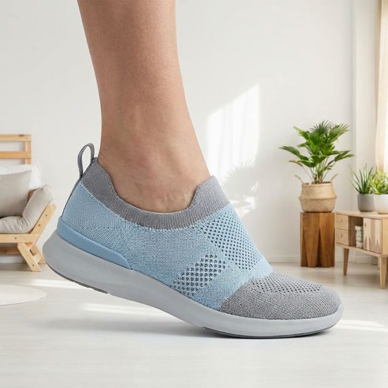 Ein Fuß gleitet mühelos in einen innovativen Hands-Free-Schuh, dessen Fersenteil sich flexibel anpasst. Helle, freundliche Umgebung.